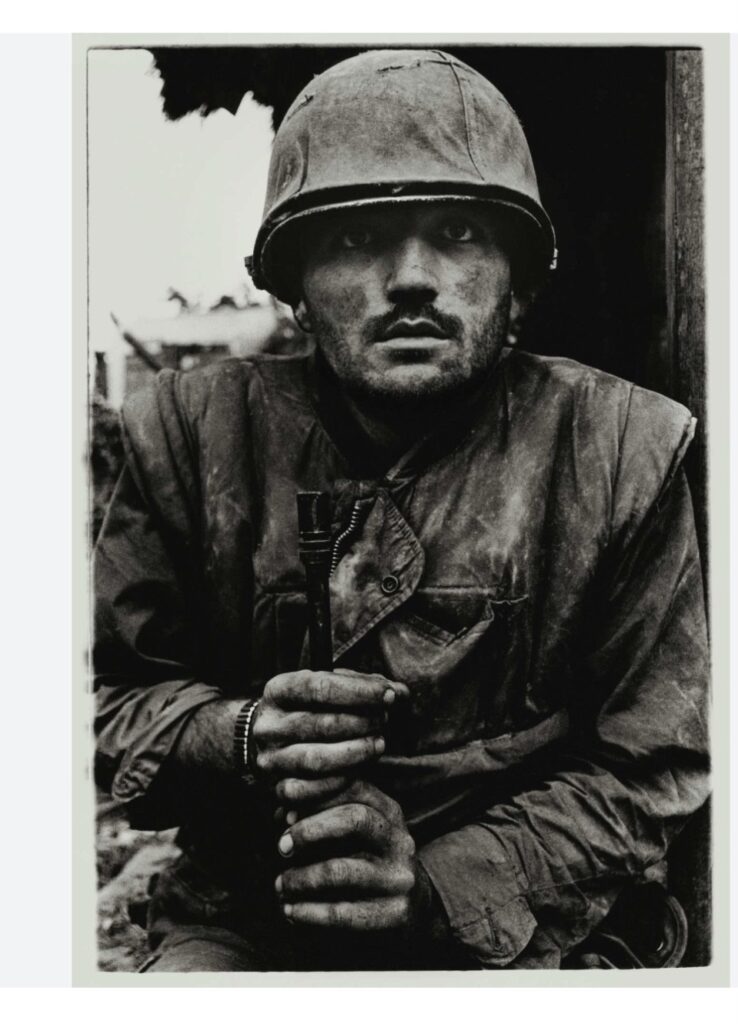 Black-and-white photo of a young US marine with a vacant stare, showing signs of trauma during the Vietnam War.