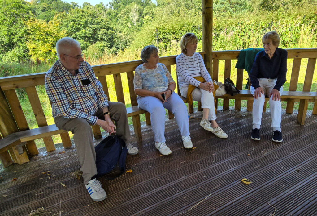 some members relaxing on a bench in the sun